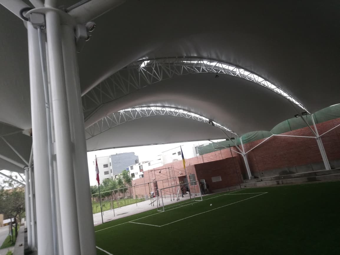 Cobertura tensionada con arcos metálicos sobre complejo deportivo
