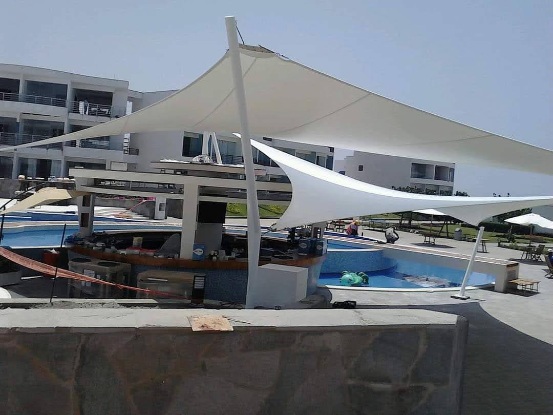 Cobertura tensionada tipo vela en área de piscina